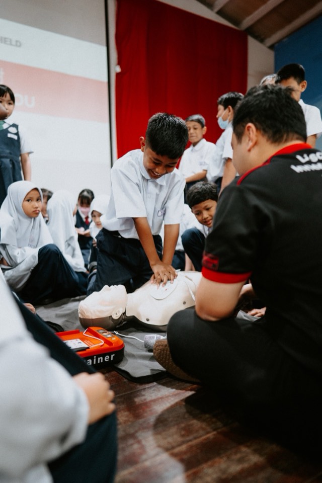 School pupils practising CPR with an AED trainer during a MediShield session