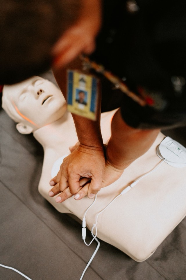 Hands locked for chest compressions on a manikin with training pads attached