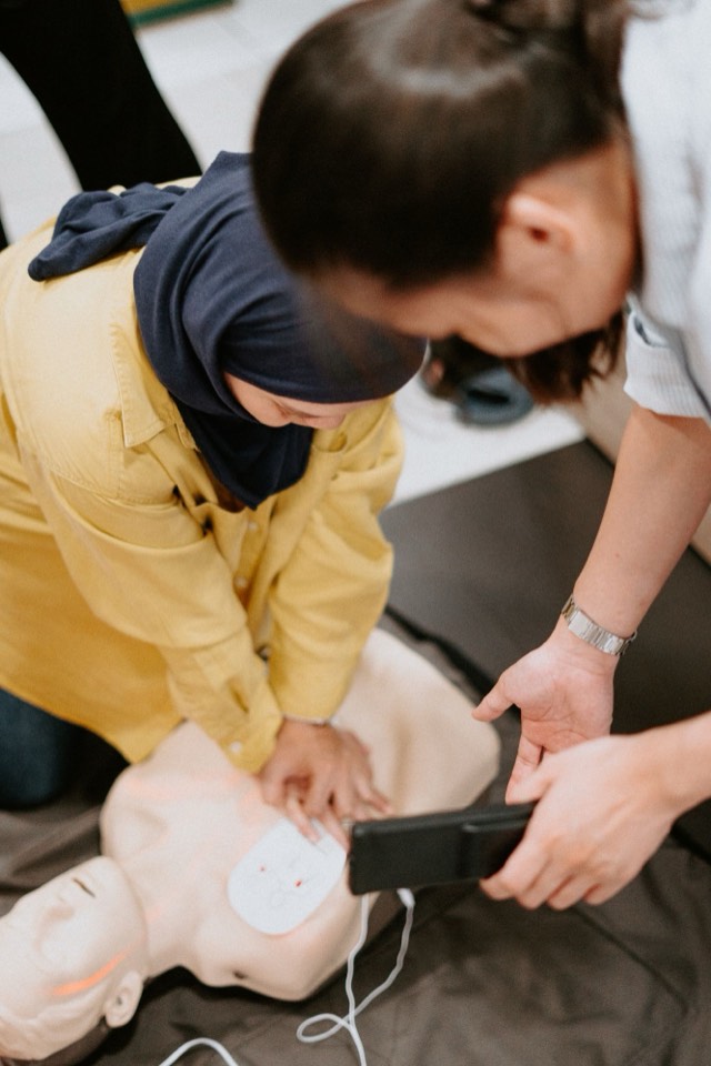 A participant practising compressions while a trainer checks feedback